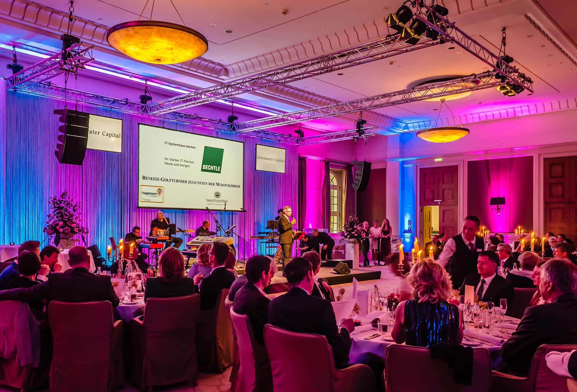 Bestuhlter Veranstaltungsraum mit Personen und Bühne